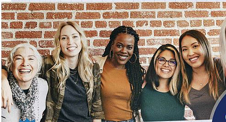 fünf Frauen lachend vor einer Mauer